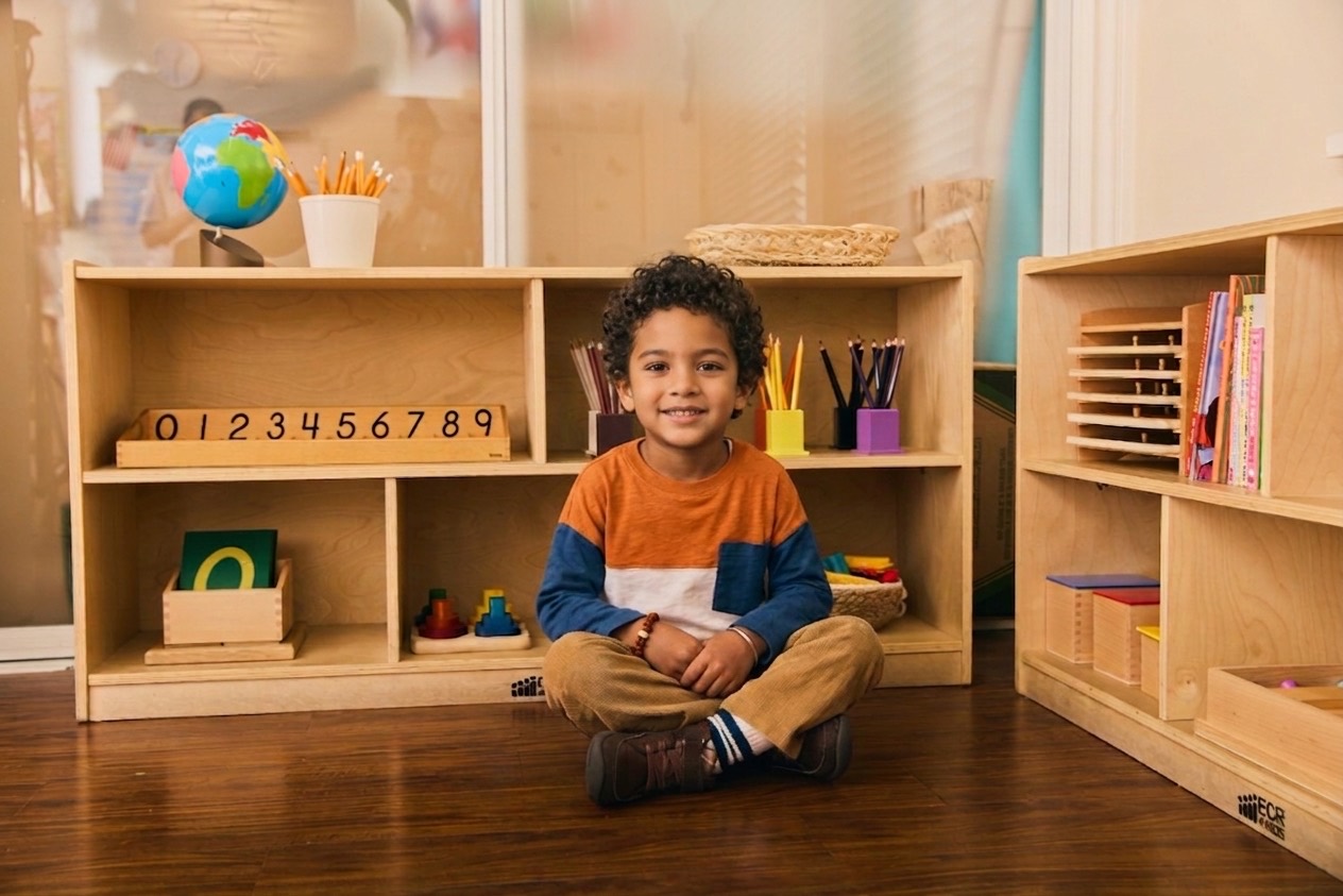 A child sitting among the open shelves of an evergreen classroom